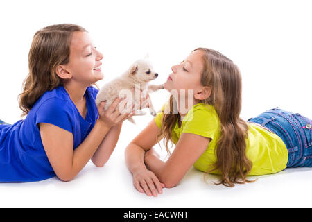 Heureux soeur jumelle kid filles et petit chien couché jouant sur fond blanc Banque D'Images