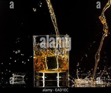 Verser dans un verre à whisky, isolé sur fond noir Banque D'Images