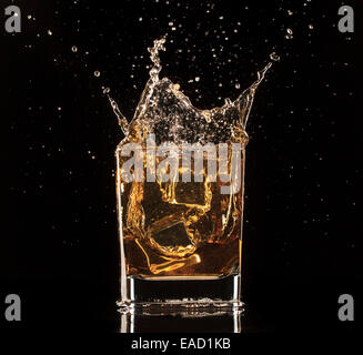 Shot de whiskey isolé avec splash sur fond noir Banque D'Images