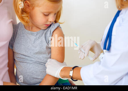 Médecin vaccinant petite fille rousse. Banque D'Images