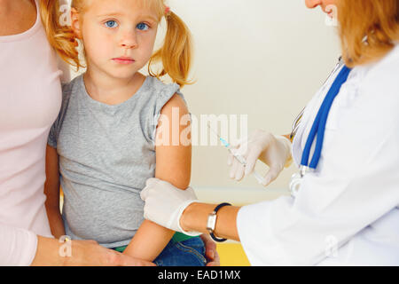 Médecin vaccinant petite fille rousse. Banque D'Images