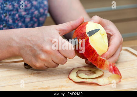 Les mains d'un peeling apple cuisson sur une planche en bois Banque D'Images