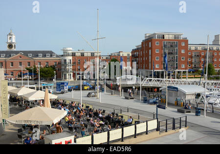 Les gens assis à des tables à l'extérieur de la zone de restaurant au centre commercial GUNWHARF QUAYS. Portsmouth. Le Hampshire. L'Angleterre. Avec apar Banque D'Images