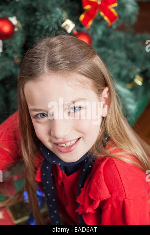 Jolie fille assise à côté de l'arbre de Noël Banque D'Images