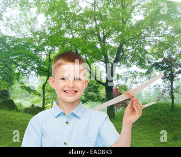 Smiling little boy holding un modèle d'avion en bois Banque D'Images