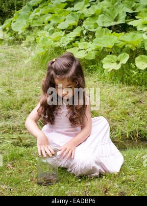 Jeune fille avec grenouille dans jar dans pays Banque D'Images