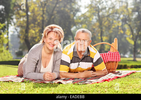 Mature couple lying on a blanket un bénéficiant d'un pique-nique dans le parc Banque D'Images