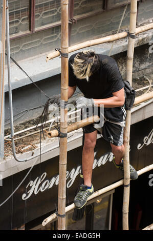 Bâtiment de l'homme en liant les échafaudages de bambou longueurs ensemble, Hong Kong. Banque D'Images