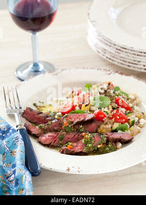 Boeuf grillé et salade de couscous avec verre de vin rouge. Banque D'Images