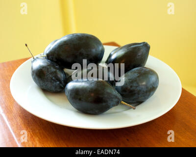 Les prunes noires sur plaque blanche dans la cuisine Banque D'Images