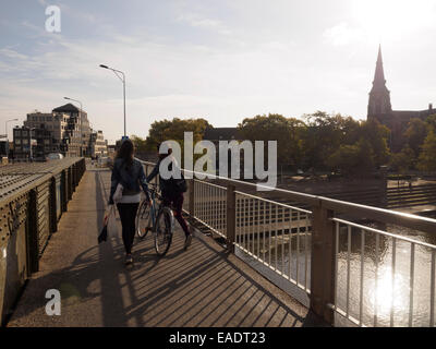 Vue arrière de deux jeunes femmes avec location traversant le pont Wilhelminabrug à Maastricht, aux Pays-Bas Banque D'Images