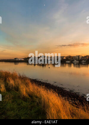 Coucher de soleil sur l'estuaire de Crouch dépeignant Hullbridge le long de la rivière jusqu'à la réflexion sur une rivière calme avec la lune visible. Banque D'Images