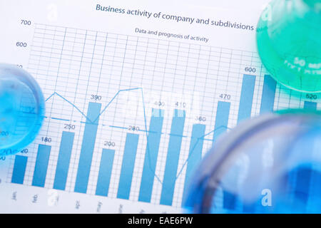 Tubes à essai avec des liquides sur le papier avec l'analyse d'affaires Banque D'Images