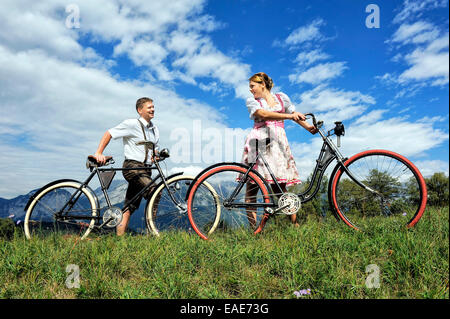 Homme portant un pantalon en cuir et d'une femme portant un dirndl avec de vieilles bicyclettes dans un paysage naturel, Innsbruck, Innsbruck, Tyrol Banque D'Images