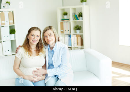 Smiling pregnant woman and her doctor looking at camera at hospital Banque D'Images