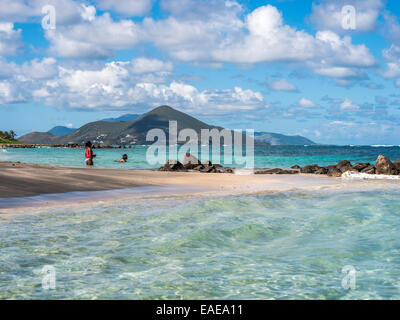 Paysage marin des Caraïbes, plage exotique location long terme Bay, Nevis avec couple baignant dans la mer bleue, St Kitts en arrière-plan. Banque D'Images