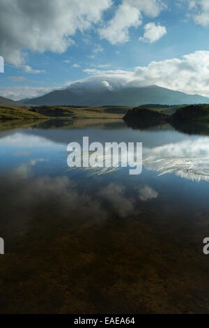 Le soleil du matin illumine le côté de Llyn Dywarchen, avec le Mont Snowdon est enveloppé dans les nuages en arrière-plan. Banque D'Images