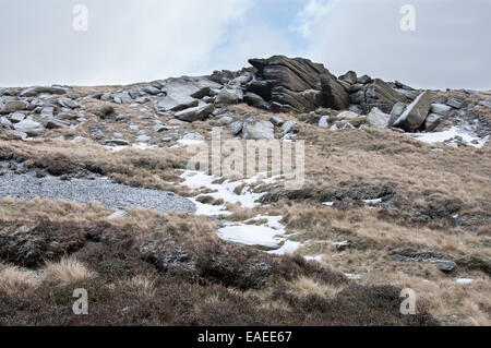 Les affleurements de roches avec des graminées lande couverte dans la première chute de neige sur Kinder scout dans le Peak District, Derbyshire. Banque D'Images