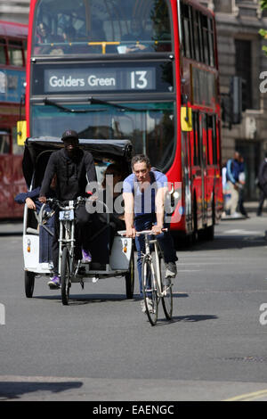 Un cycle et un cycle de déplacement en taxi en face d'une London bus rouge Banque D'Images