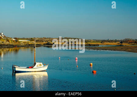 Un seul bateau flotte calmement dans l'estuaire de la mer intérieure à quatre Mile Bridge, Anglesey, Pays de Galles Banque D'Images