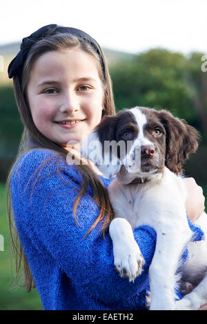 Girl Holding Animal Spaniel Puppy Outdoors In Garden Banque D'Images