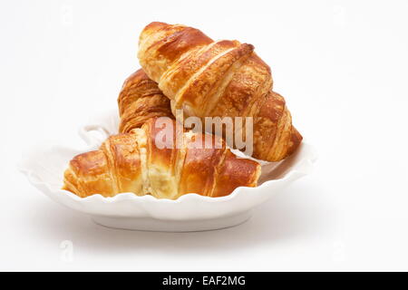 Trois croissants sur un plateau blanc sur fond blanc Banque D'Images