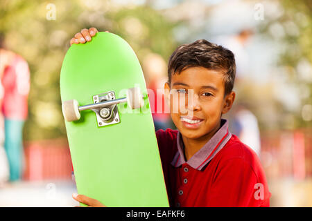 Portrait de jeune garçon arabe avec skateboard vert Banque D'Images