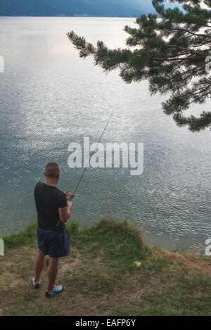 Homme avec hameçon en face de mountain dam Banque D'Images