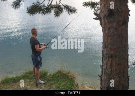 Homme avec hameçon en face de mountain dam Banque D'Images