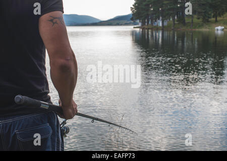 Homme avec hameçon en face de mountain dam Banque D'Images