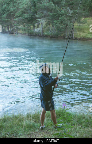 Homme avec hameçon en face de mountain dam Banque D'Images