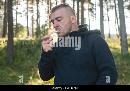 Garçon qui fume une cigarette dans la nature Banque D'Images