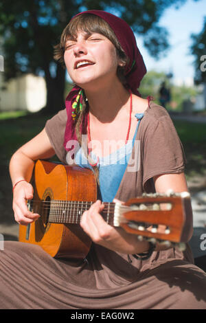 Jeune fille qui joue de la guitare dans la rue. Journée ensoleillée Banque D'Images