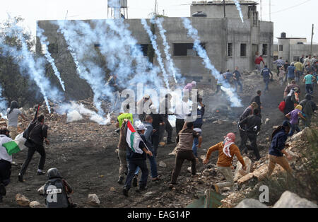 Naplouse. 14Th Nov, 2014. Des manifestants palestiniens fuient des grenades lacrymogènes tirées par des soldats israéliens lors d'affrontements dans la mécréance Qadoom village près de la ville cisjordanienne de Naplouse, le 14 novembre 2014. Des heurts ont éclaté vendredi entre manifestants palestiniens et soldats israéliens dans plusieurs villes de Cisjordanie contre les récentes mesures prises par Israël à Jérusalem. Credit : Nidal Eshtayeh/Xinhua/Alamy Live News Banque D'Images