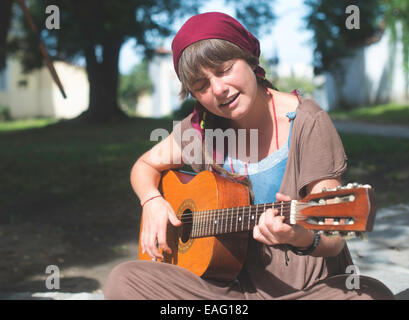 Jeune fille qui joue de la guitare dans la rue. Journée ensoleillée Banque D'Images