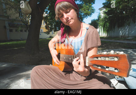 Jeune fille qui joue de la guitare dans la rue. Journée ensoleillée Banque D'Images