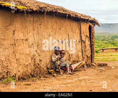 Deux garçons africains assis en face d'une maison du village de la tribu Masai Banque D'Images