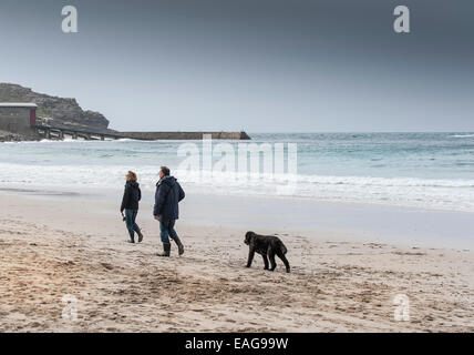 Les promeneurs de chiens sur la plage de Sennen à Cornwall. Banque D'Images