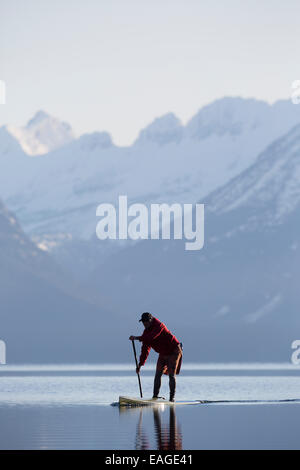 Un homme en stand up paddle (SUP) sur un lac calme McDonald dans le parc national des Glaciers. Banque D'Images