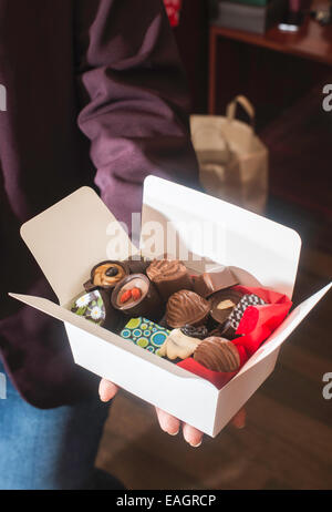 Mains tenant une boîte de chocolats. Close up Banque D'Images