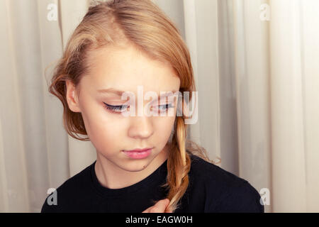 Caucasian girl blonde sourit timidement, portrait Banque D'Images