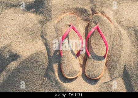 Sandales rose sur la plage dans le sable Banque D'Images