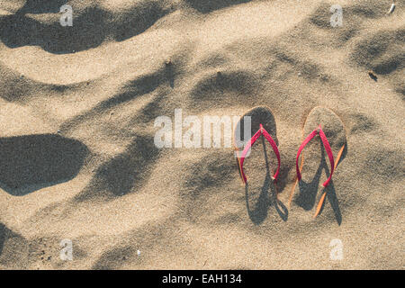 Sandales rose sur la plage dans le sable Banque D'Images
