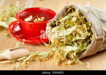 Tasse de thé et des fleurs de tilleul en toile de sac sur table en bois Banque D'Images