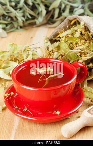 Tasse de thé et des fleurs de tilleul en toile de sac sur table en bois Banque D'Images