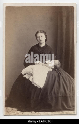 Victorian, sur carton, portrait d'une jeune femme, berçant un bébé. Prises dans le studio de Weston-Super-Mare, Royaume-Uni, vers 1870 Banque D'Images