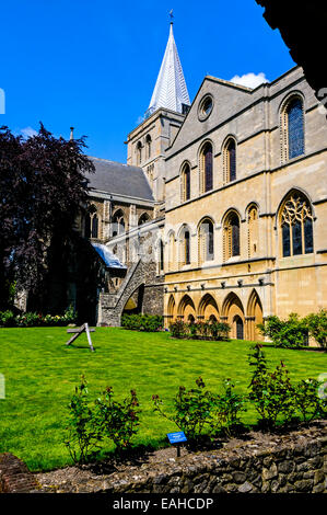 L'imposante façade de la cathédrale de Rochester montrant la salle du chapitre et le jardin avec une croix de bois sur une pelouse tondue Banque D'Images