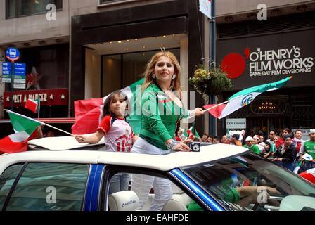 NYC : Mère et fille brandissant des drapeaux à travers le toit ouvrant d'une voiture à l'assemblée annuelle de l'indépendance mexicaine Day Parade Banque D'Images