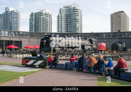 Petit train passant devant loco de vapeur 6213 à la Rotonde de John Street, Toronto Railway Heritage Centre, Ontario, Canada Banque D'Images