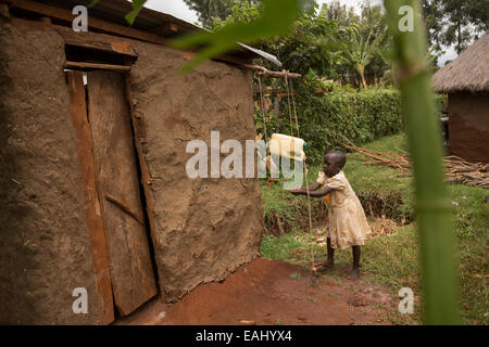 Une jeune fille se lave les mains à l'aide d'un robinet-tippy dans Bukwo, District de l'Ouganda, l'Afrique de l'Est. Banque D'Images